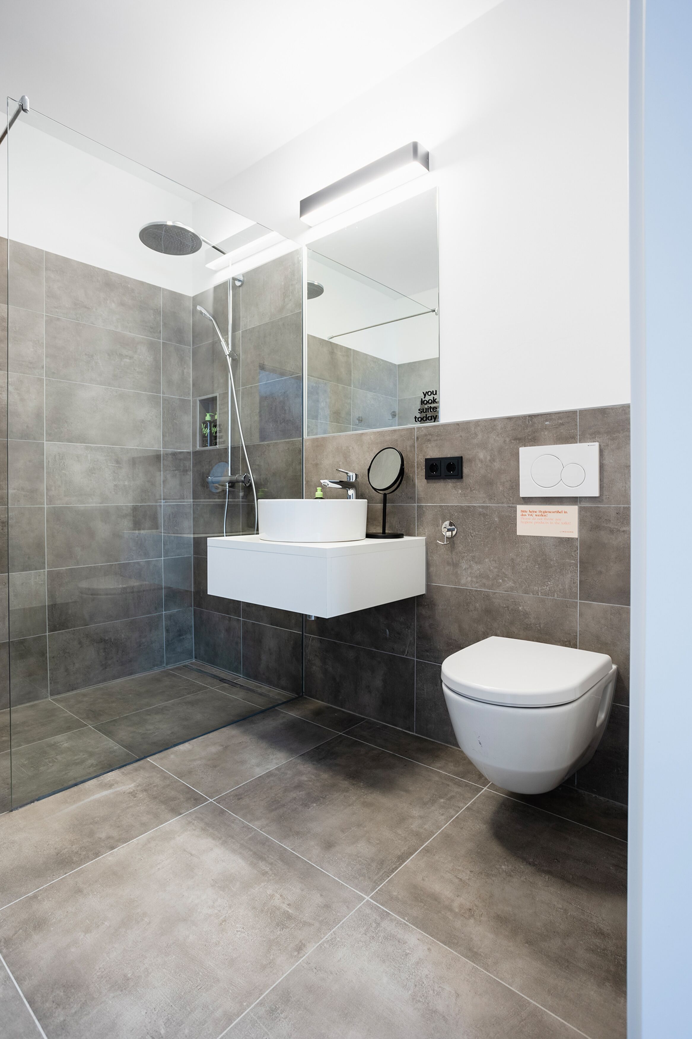 A modern bathroom with a glass-enclosed shower, a white sink, and a toilet.