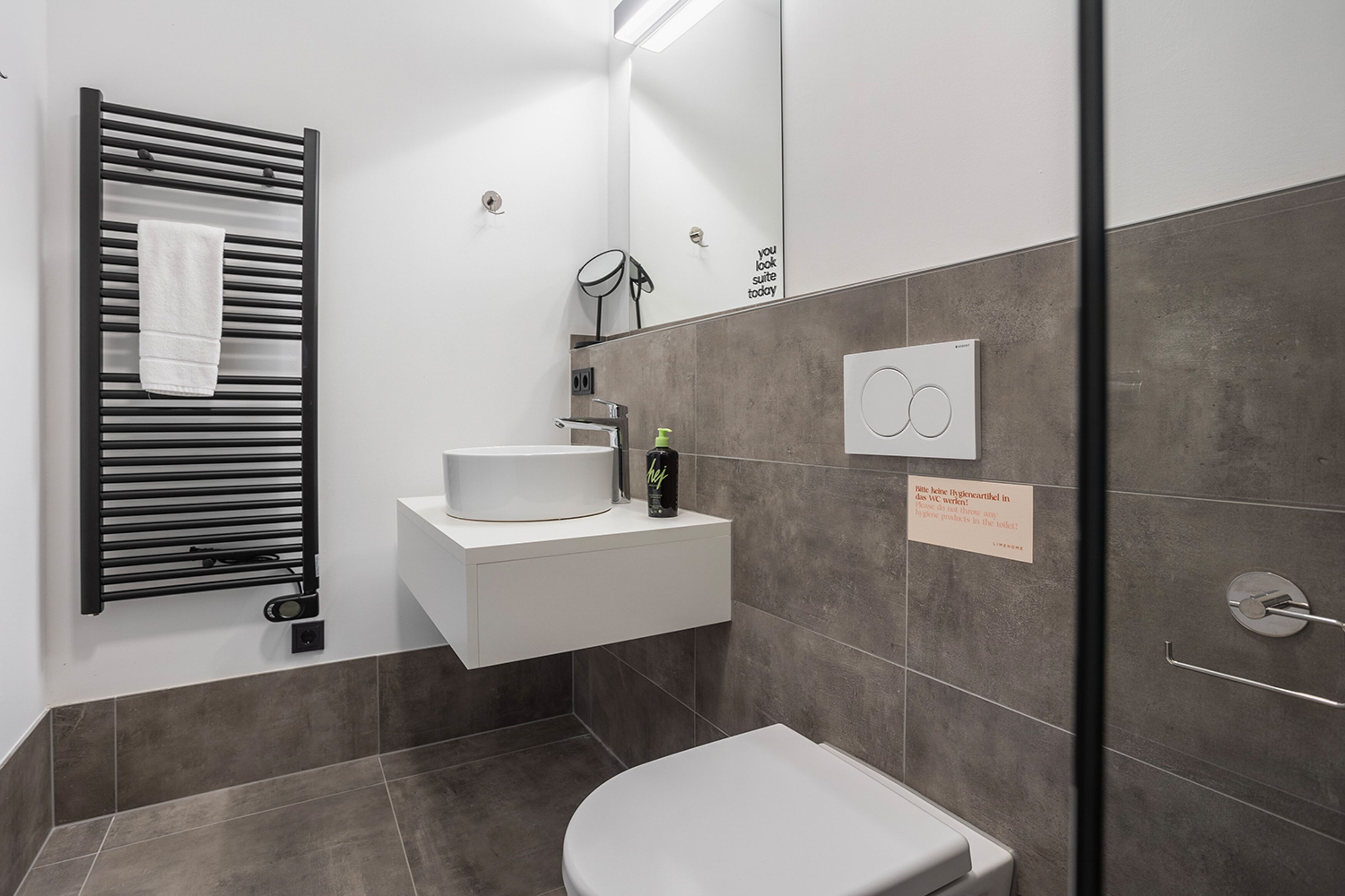 A modern bathroom with a towel rack, sink, and toilet.