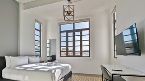 A bedroom with a bed, a desk, and a TV. - w* | Premium 1BR in Casco Antiguo (Panamá)