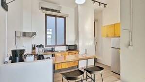 A modern kitchen with a central island, bar stools, and a window. - w* | Premium 1BR in Casco Antiguo (Panamá)