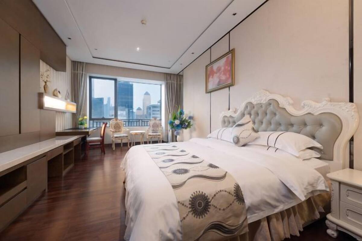 A hotel room with a large bed, a desk, and a view of the city.