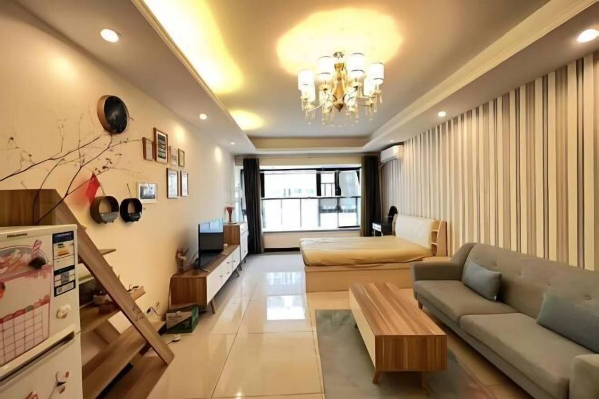 A modern living room with a sofa, a coffee table, a TV, and a staircase.