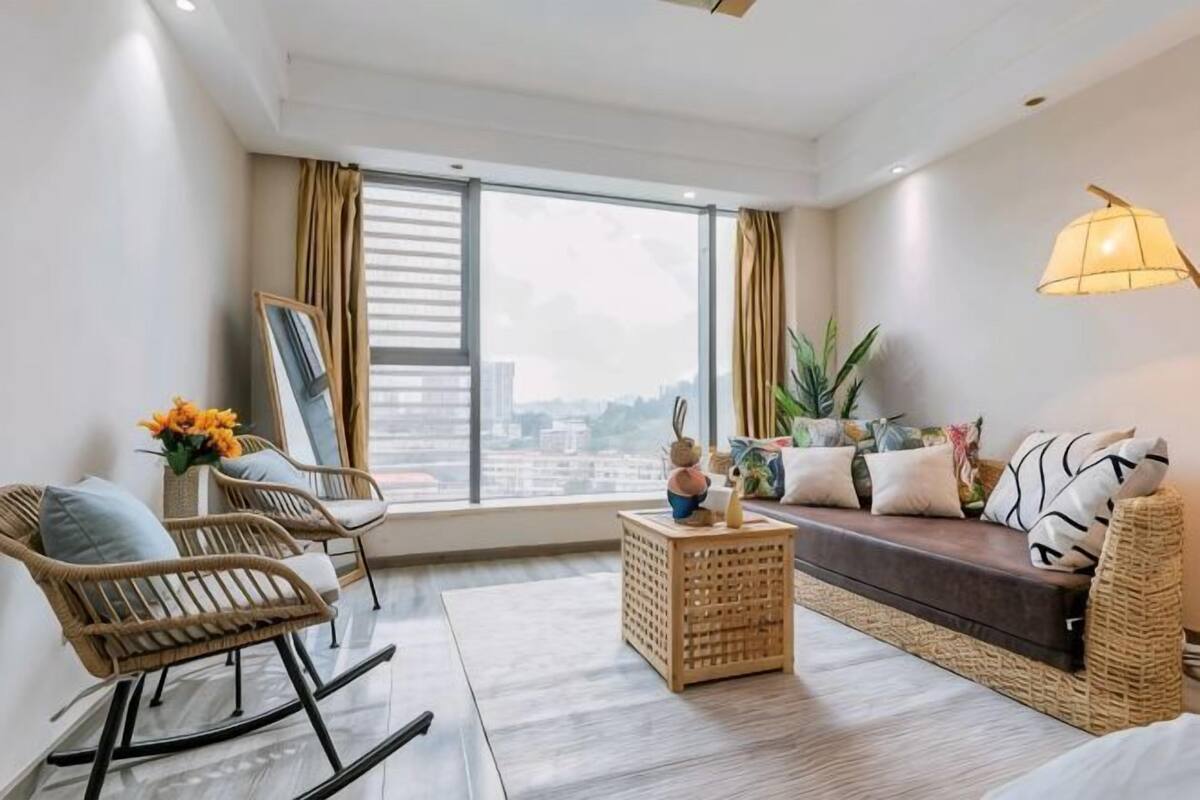 A modern living room with a large window, a sofa, a coffee table, and a rocking chair.