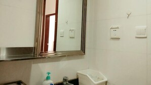 A bathroom with a mirror, a sink, a toilet, and a bottle of hand sanitizer.