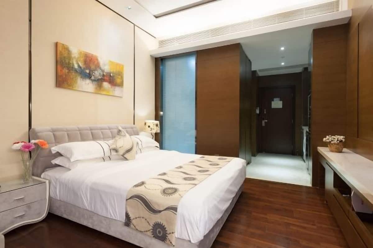 A modern hotel room with a bed, bedside table, and a painting on the wall.