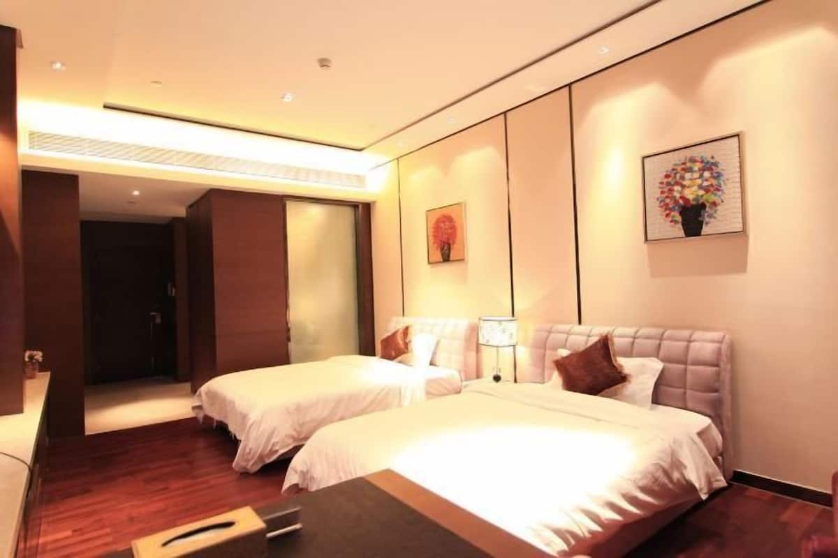 A hotel room with two beds, a bedside table, a nightstand, and a large window.