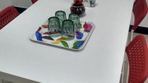 A white table with a colorful tray holding several glass jars.