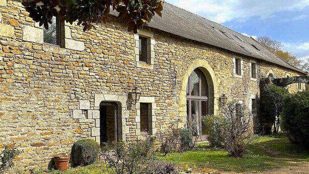A stone building with a gravel driveway and a small garden area.