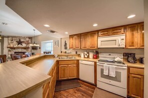 Una cucina con mobili in legno, un'isola integrata, un forno a microonde, un fornello e una lavastoviglie.