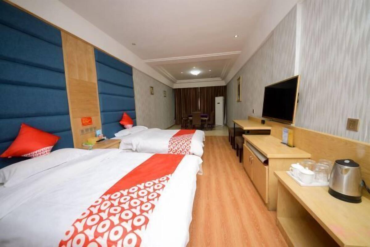 A hotel room with two beds, a desk, a TV, and a coffee maker.