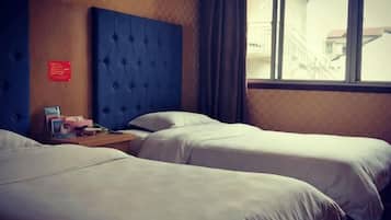 A hotel room with two beds, a wooden headboard, a nightstand, and a window with a view of a building outside.