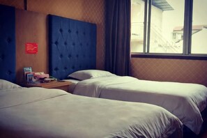A hotel room with two beds, a wooden headboard, a nightstand, and a window with a view of a building outside. - Taoyuan Supreme Hotel (Taoyuan)