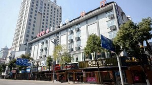 A multi-story hotel with a prominent 'OYO' sign on the facade, surrounded by various storefronts and trees along the street. - Taoyuan Supreme Hotel (Taoyuan)