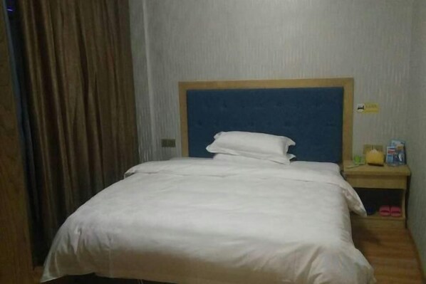 A hotel room with a bed, a nightstand, and a curtain. - Taoyuan Supreme Hotel (Taoyuan)