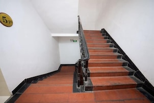 A staircase with a handrail, a landing with a sign, and a wall-mounted number plate.