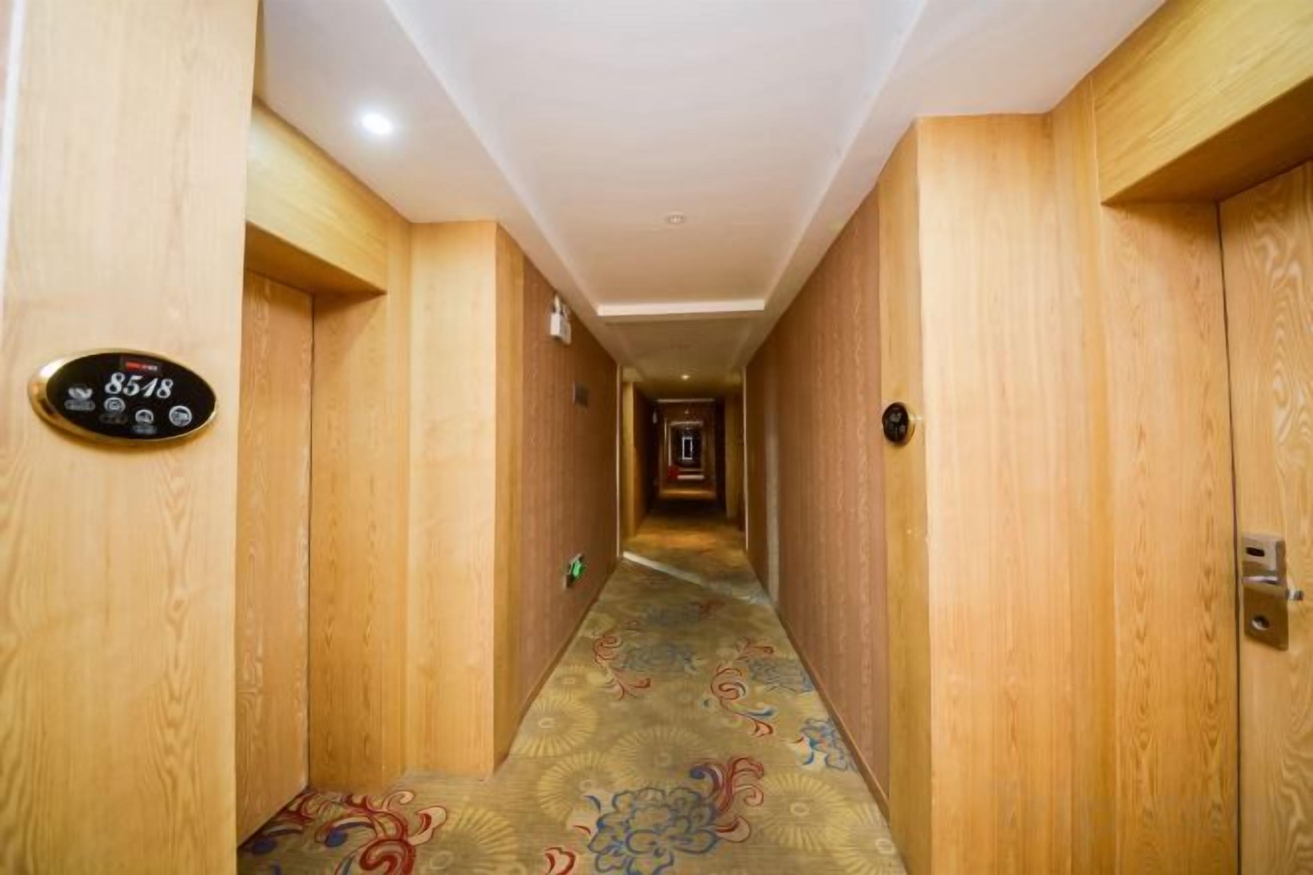 A hotel hallway with wooden walls and a carpeted floor.