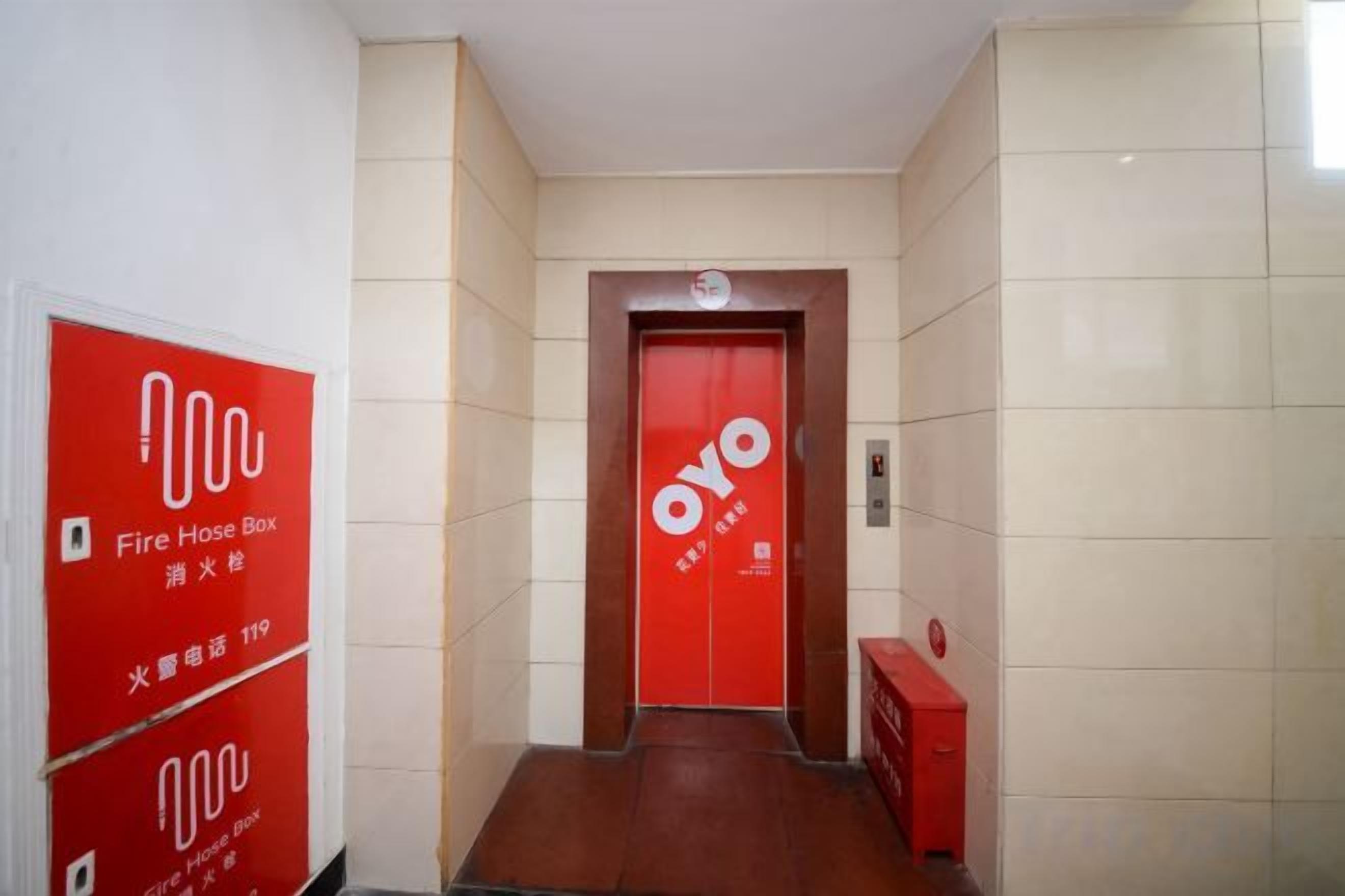 A hallway with a red door labeled 'Oyo' and red fire hose boxes on the walls.