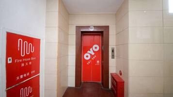 A hallway with a red door labeled 'Oyo' and red fire hose boxes on the walls.