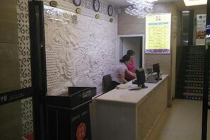 A reception desk with a decorative wall, a computer, and a menu board. - Taoyuan Supreme Hotel (Taoyuan)