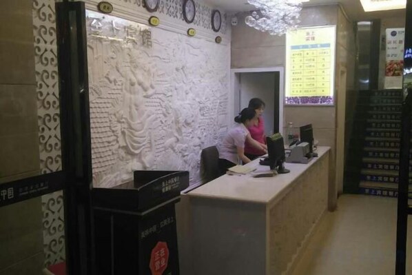 Una recepción con un muro decorativo, una computadora y una pizarra con la carta.