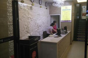 Una recepción con un muro decorativo, una computadora y una pizarra con la carta.