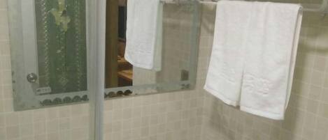 Un baño con lavamanos, espejo y perchero para toallas.