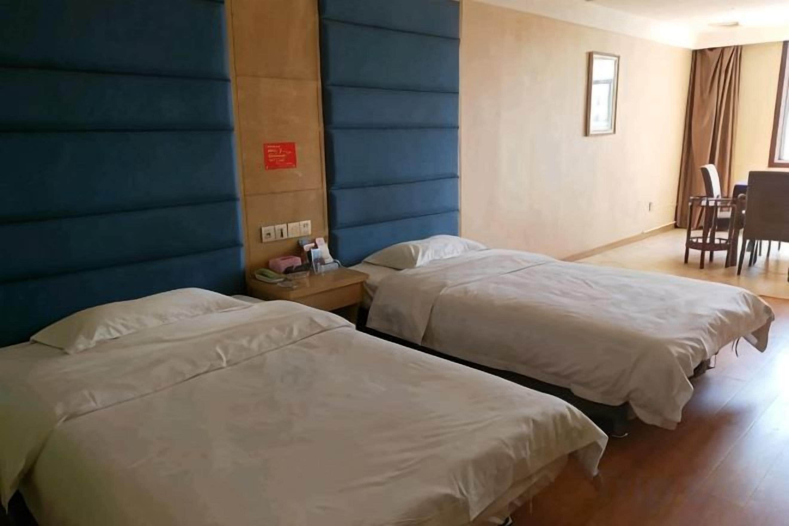 A hotel room with two beds, a desk, and a chair.