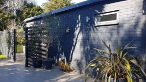 Un bâtiment moderne à la façade bleu foncé, doté d’un portail en métal et agrémenté de plantes en pot.