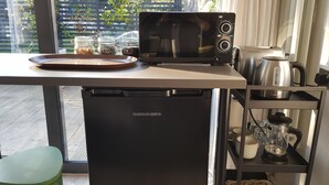 Une petite cuisine équipée comprenant un micro-ondes noir, une machine à café et un petit réfrigérateur.
