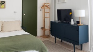 Une chambre à coucher avec un lit, une commode, un téléviseur et un porte-manteau.
