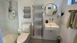 Une salle de bain moderne équipée d’une douche, de toilettes, d’un lavabo et d’un porte-serviettes.