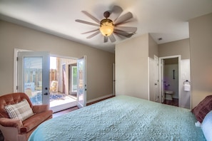 A bedroom with a large bed, a ceiling fan, and a view of the outside through an open door. - Ss 6b Teckelhaus 2 Bedroom Condo by RedAwning (New Braunfels)