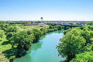 A river with a bridge, surrounded by greenery and buildings. - Ss 6b Teckelhaus 2 Bedroom Condo by RedAwning (New Braunfels)