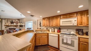 A kitchen with wooden cabinets, a built-in island, a microwave, a stove, and a dishwasher.