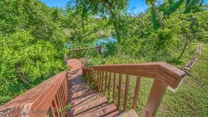 A wooden staircase leading to a scenic overlook with a view of a lake surrounded by lush greenery.