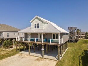 A beachfront house with a covered porch and outdoor seating.