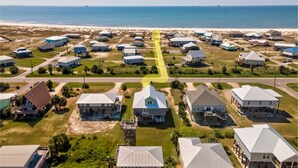 An aerial view of a coastal residential area with houses, a beach, and a clear sky.