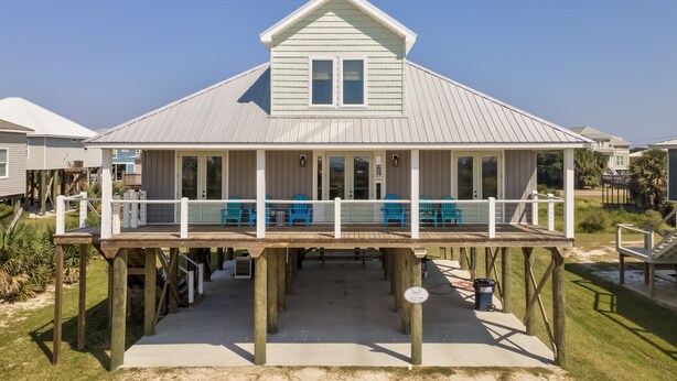 A coastal house with a covered porch and multiple blue chairs.
