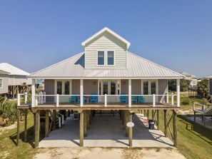 A coastal house with a covered porch and multiple blue chairs.