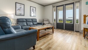A living room with a blue sofa, a wooden coffee table, and two framed bird paintings on the wall.