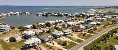 An aerial view of a coastal residential area with houses, a marina, and a bridge.