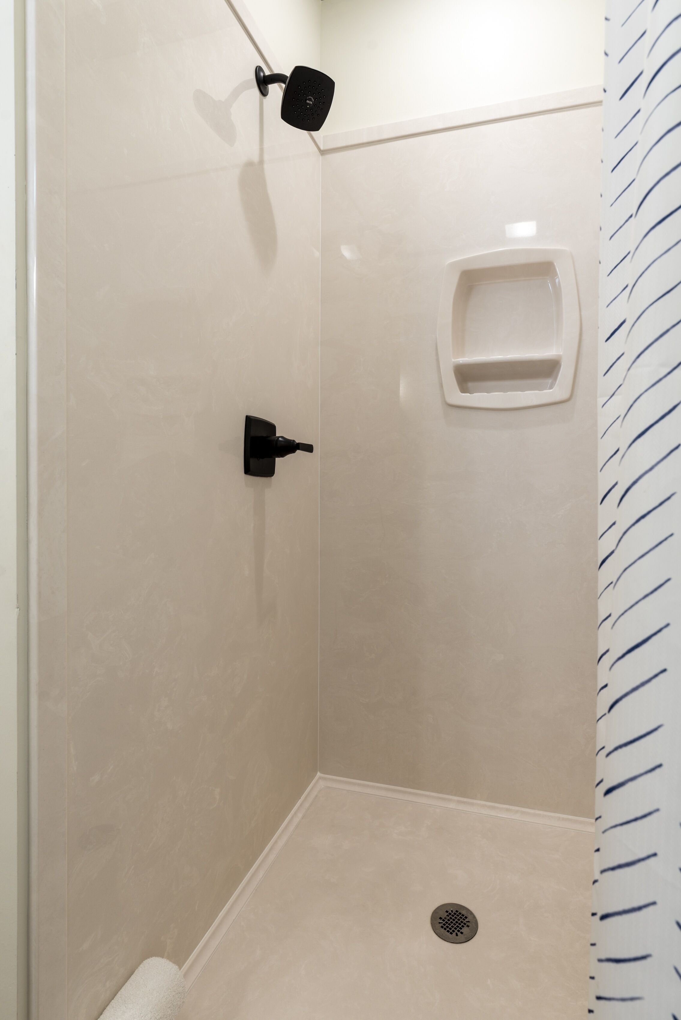 A small, enclosed shower area with a wall-mounted showerhead and a built-in soap dish.