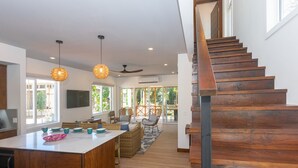 A spacious kitchen with a large island, wooden staircase, and large windows allowing natural light. - Casa Palmera 2 Bedroom Home by RedAwning (Roatan)