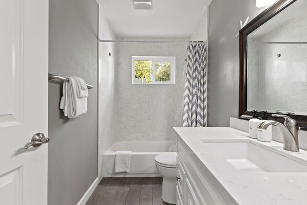 A modern bathroom with a bathtub, toilet, and vanity.