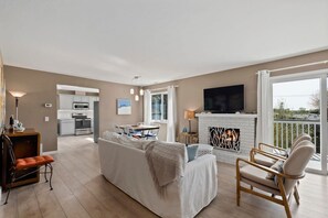 A modern living room with a sofa, armchairs, a fireplace, and a kitchen in the background. - The Boardwalk Haven - Santa Cruz, CA (Santa Cruz)