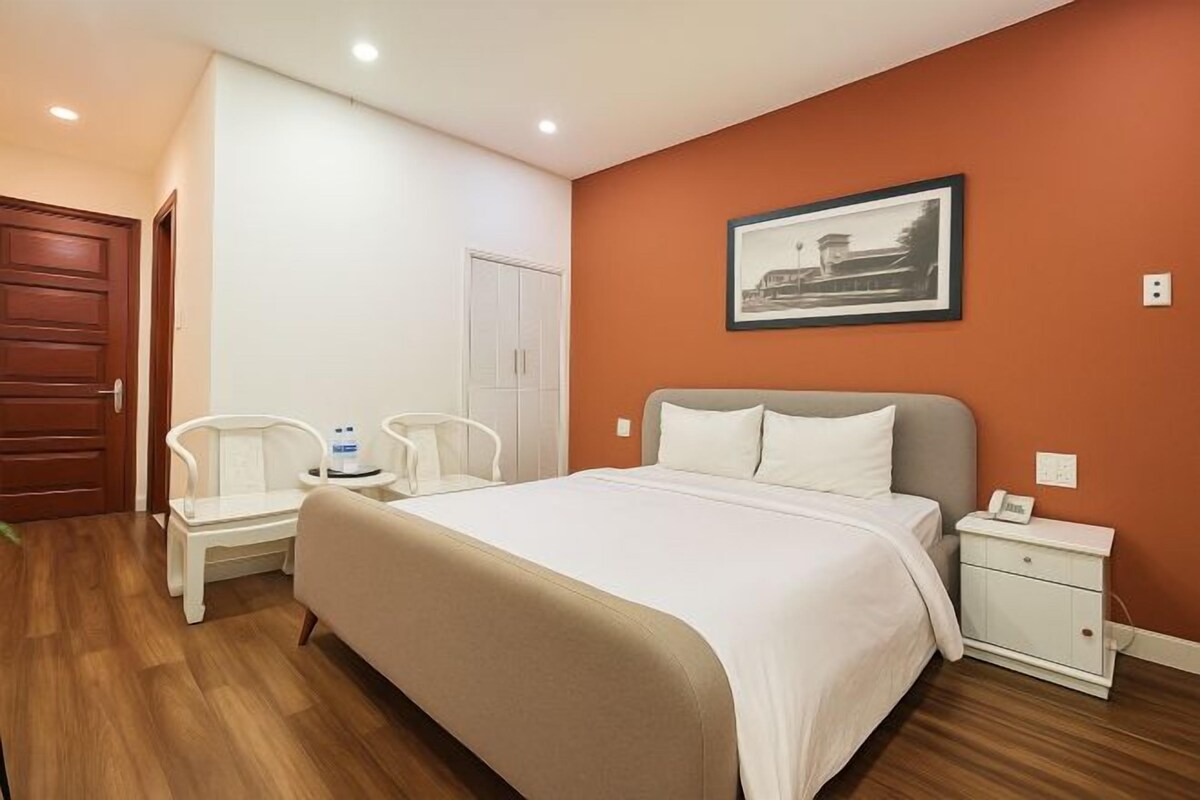 Een slaapkamer met een groot bed, een nachtkastje, een stoel en een kledingkast.