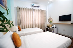 Quarto de hotel com duas camas, televisão, uma mesinha com chaleira e ar-condicionado instalado na parede.