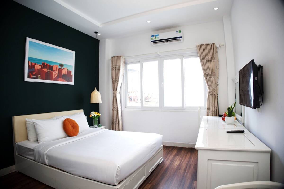 A hotel room with a bed, a desk, a TV, and a window with curtains.