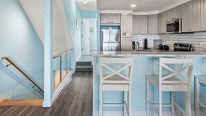 Une cuisine moderne dotée d’un îlot central, d’appareils électroménagers en acier inoxydable et de murs bleu clair.