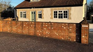 A two-story building with a brick wall and a tiled roof. - The Lodge, South Cotswolds, contemporary rural home, Spa Pool, views, parking (Chippenham)